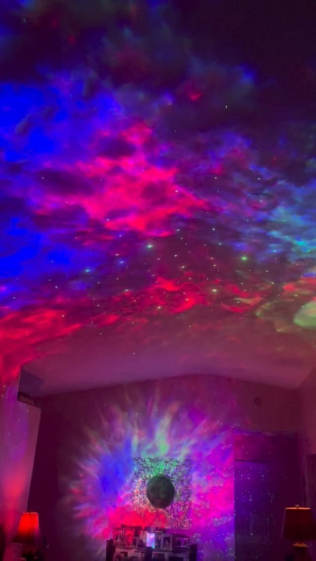 Colorful galaxy projector lights illuminating a room ceiling and wall in pink and blue