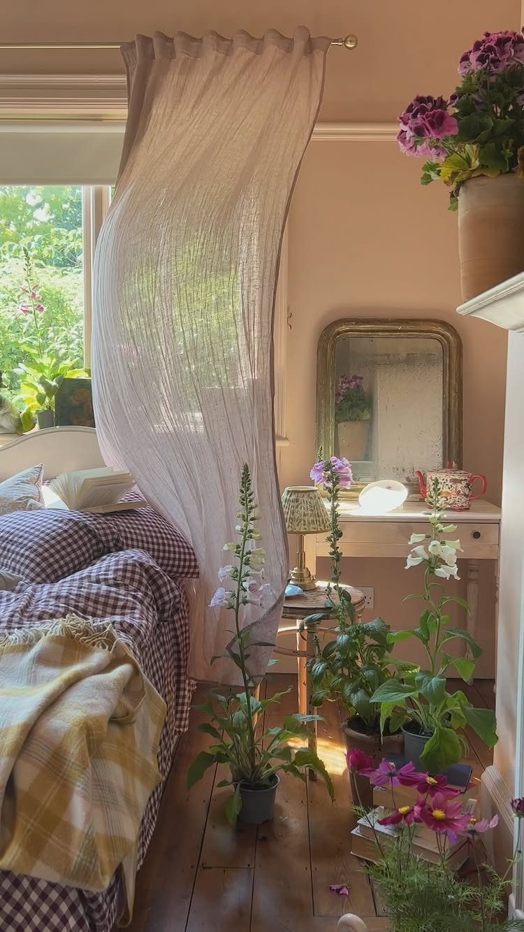 Sheer white curtains filtering natural light into a pink bedroom with plants.