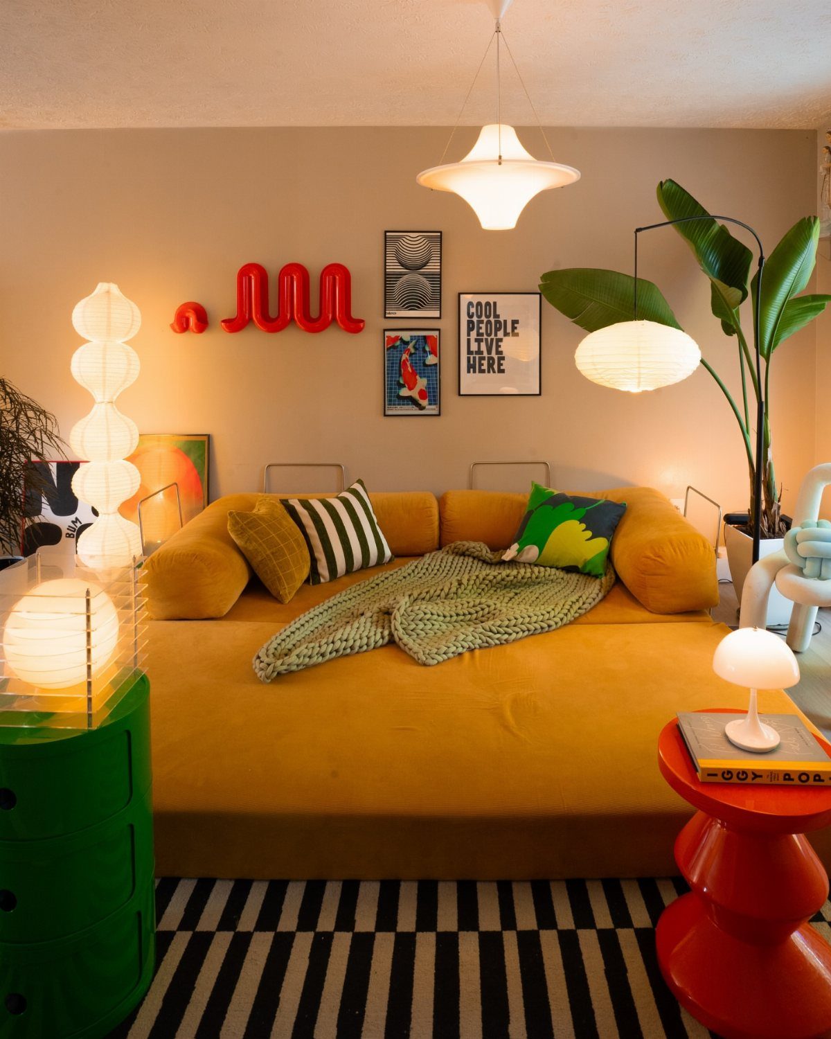 Mustard yellow daybed with colorful pillows and lamps in a modern eclectic room.