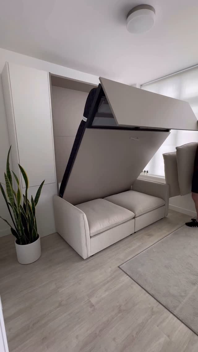 Beige Murphy bed folding down over a matching sofa in a modern room.