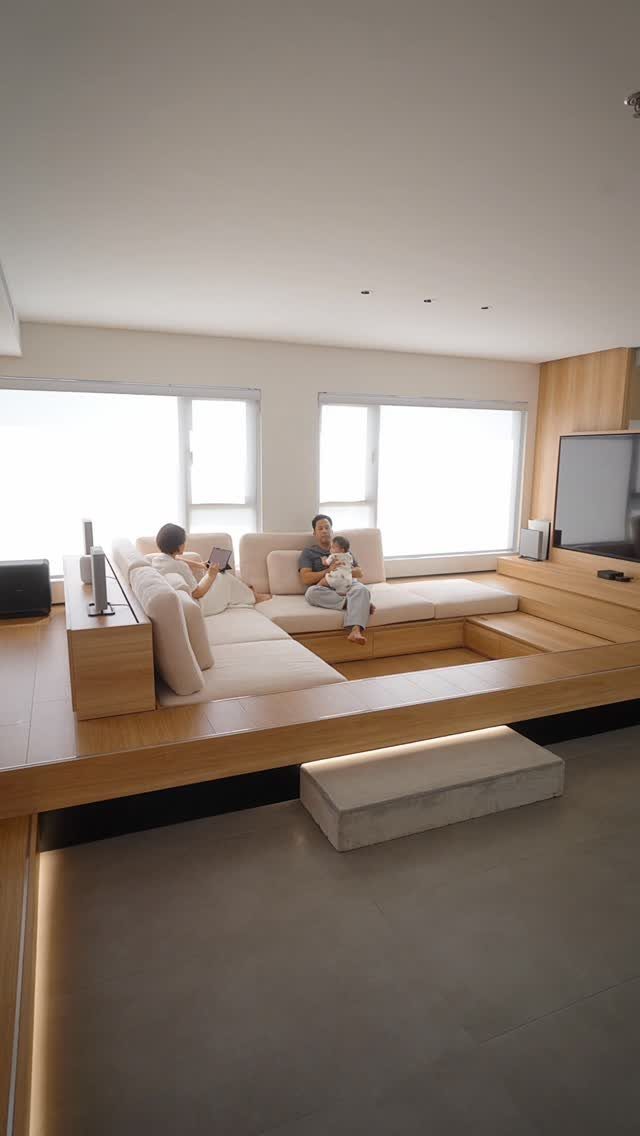 Modern minimalist room with a raised wooden platform combining a sofa and bed area.