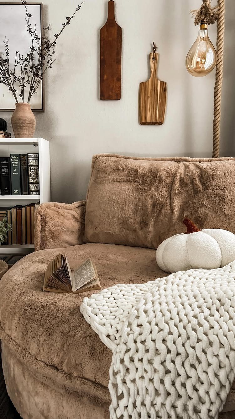 Brown faux-fur armchair with an open book, white blanket, and cozy lighting.