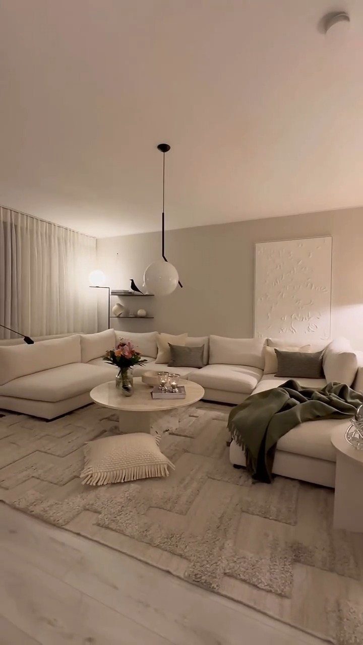 White sectional sofa and round coffee table illuminated by warm globe pendant lighting.