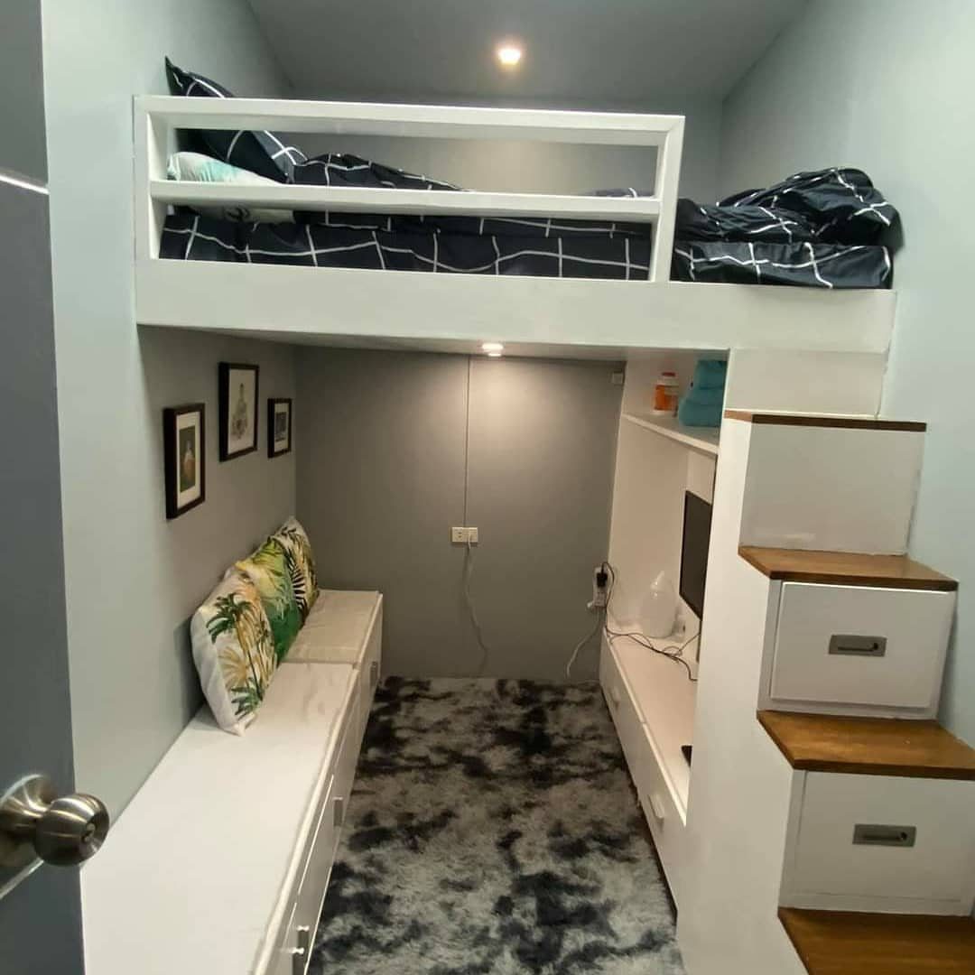 White loft bed with safety railing over a cozy seating and desk area.