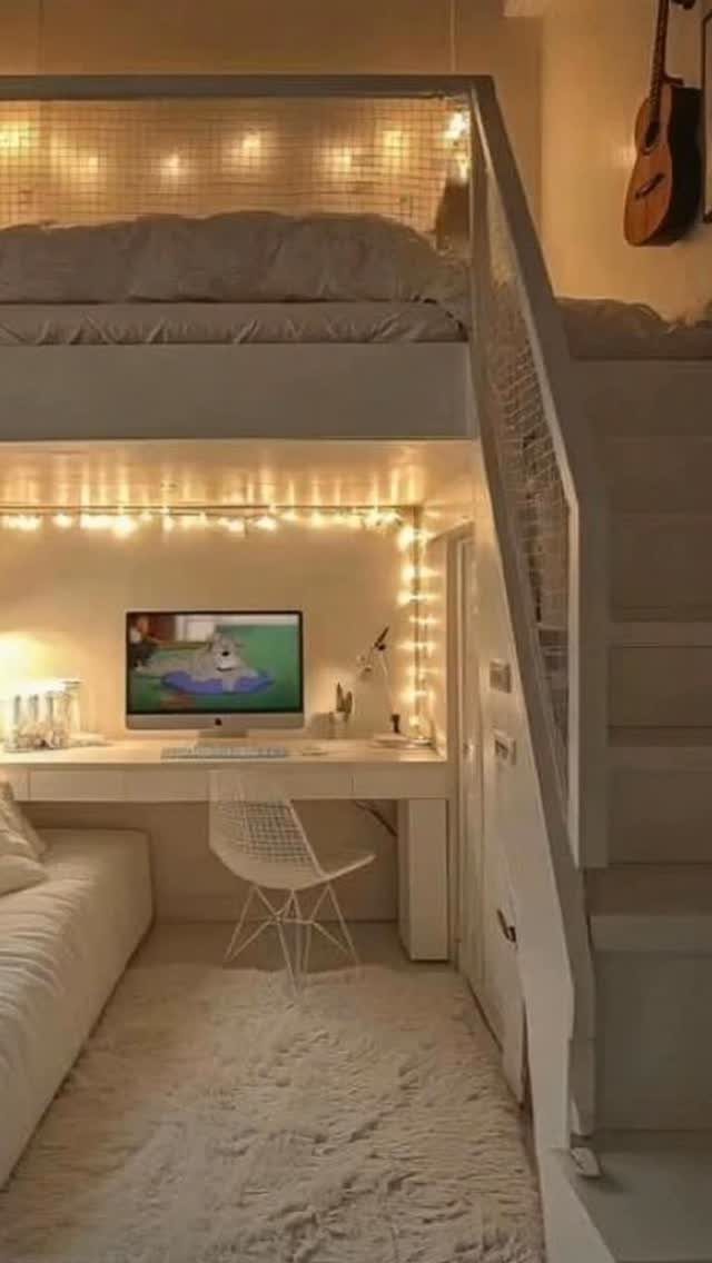 White wooden loft bed with a desk, computer, and cozy lighting underneath.