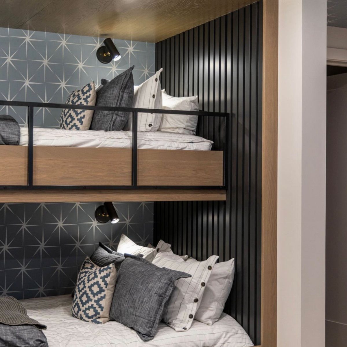 Wooden loft bed with black metal rails and blue star-patterned wallpaper background