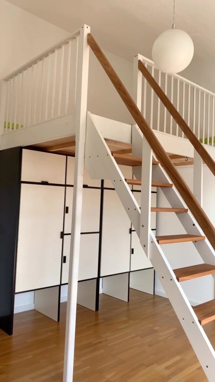White wooden loft bed with integrated stairs and storage cabinets underneath.