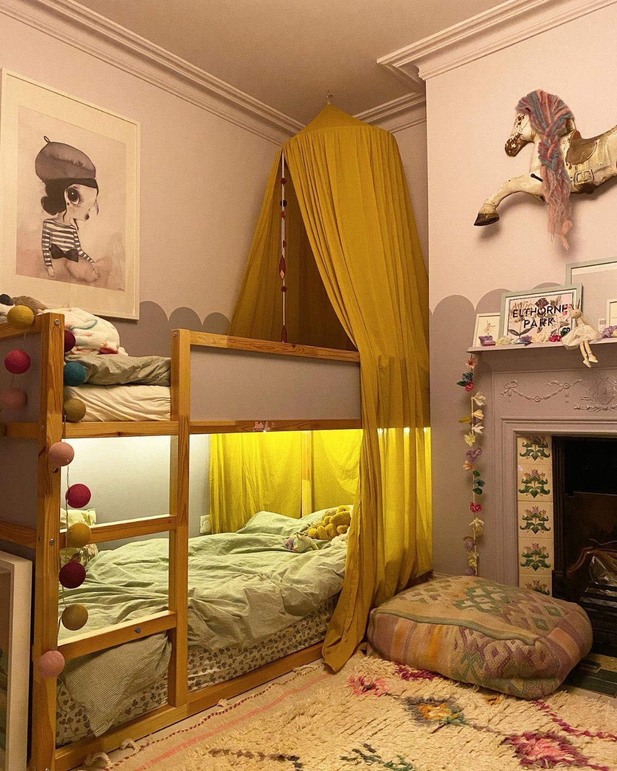 Wooden loft bed with yellow curtains draped over the top and bottom bunks.