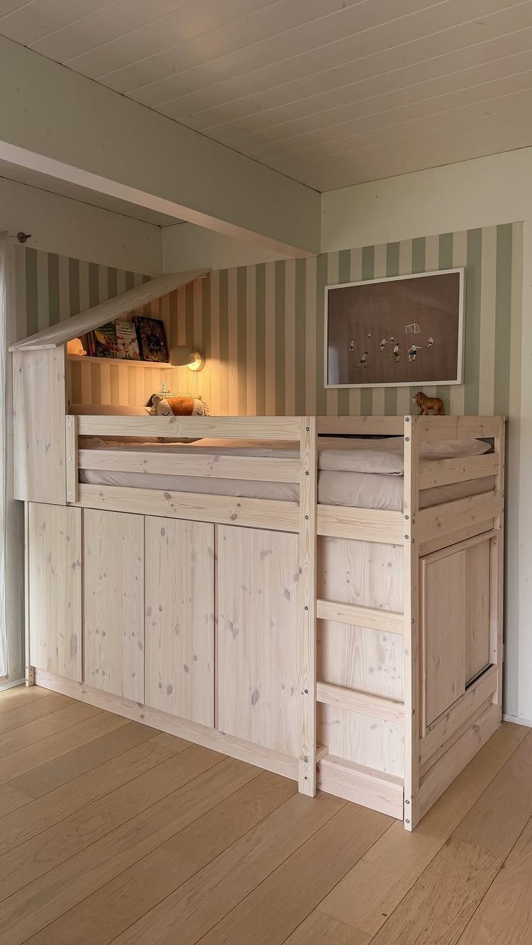 Wooden loft bed with integrated storage cabinets and a ladder against striped walls.