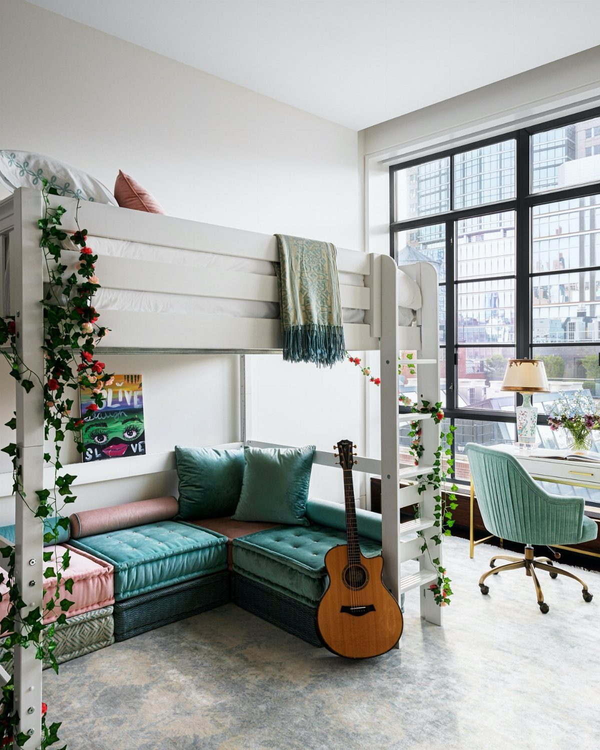 White loft bed with a teal sectional sofa and guitar underneath in a bright room