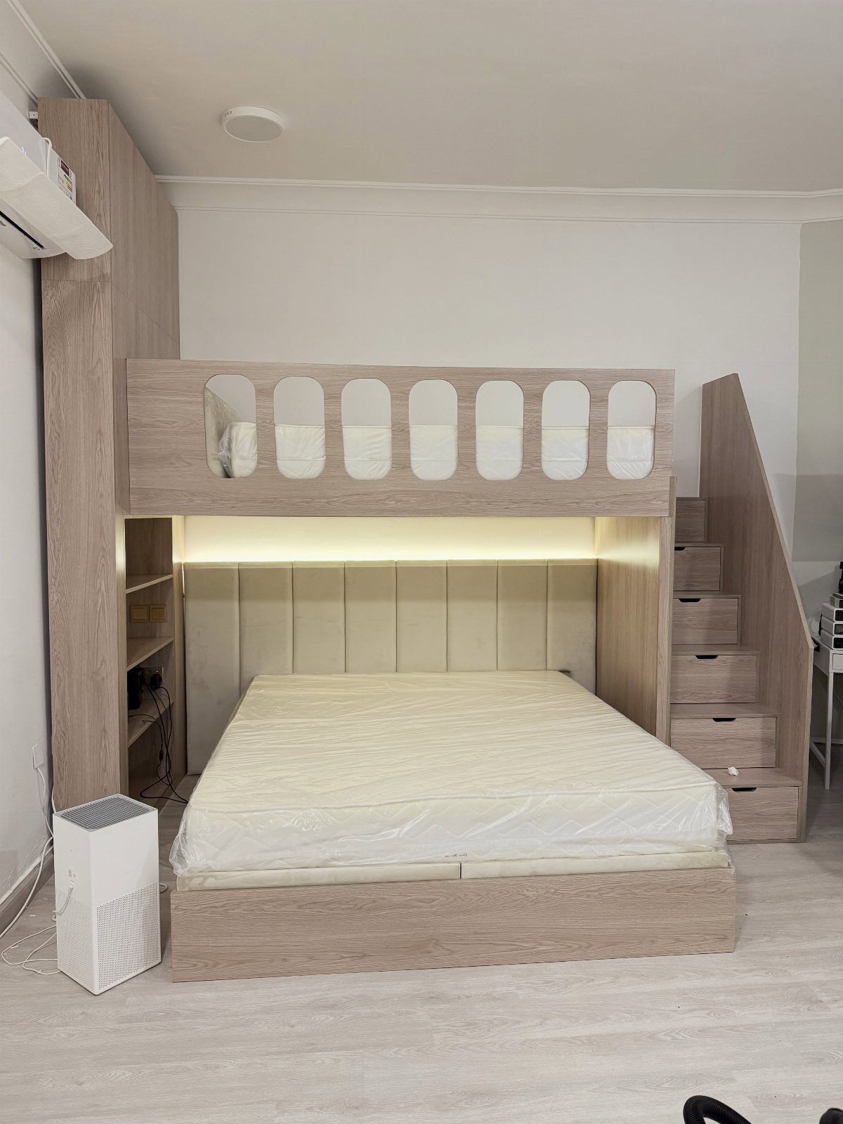 Light wood loft bed with a lower bed and integrated storage stairway.