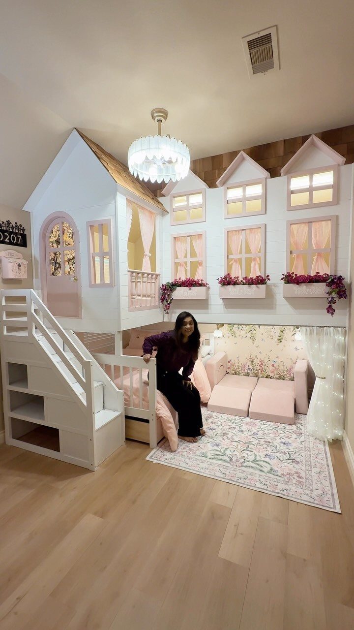 House-shaped white loft bed with a pink cozy reading nook and seating below.