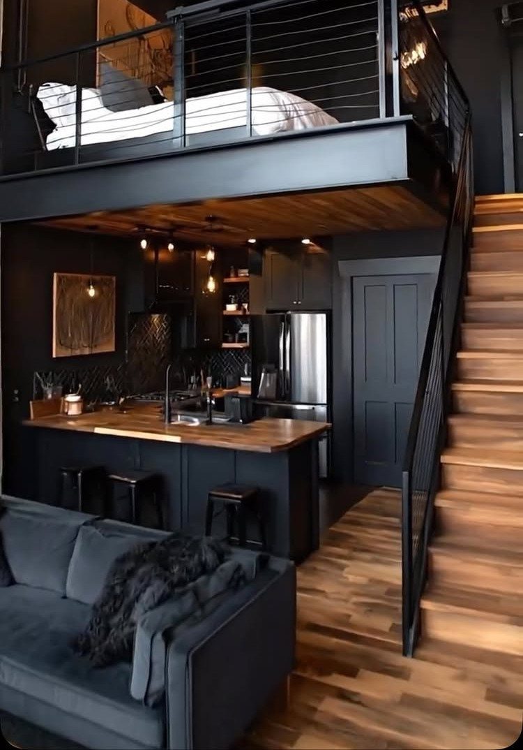 Black metal loft bed overlooking a modern dark kitchen and living room area.