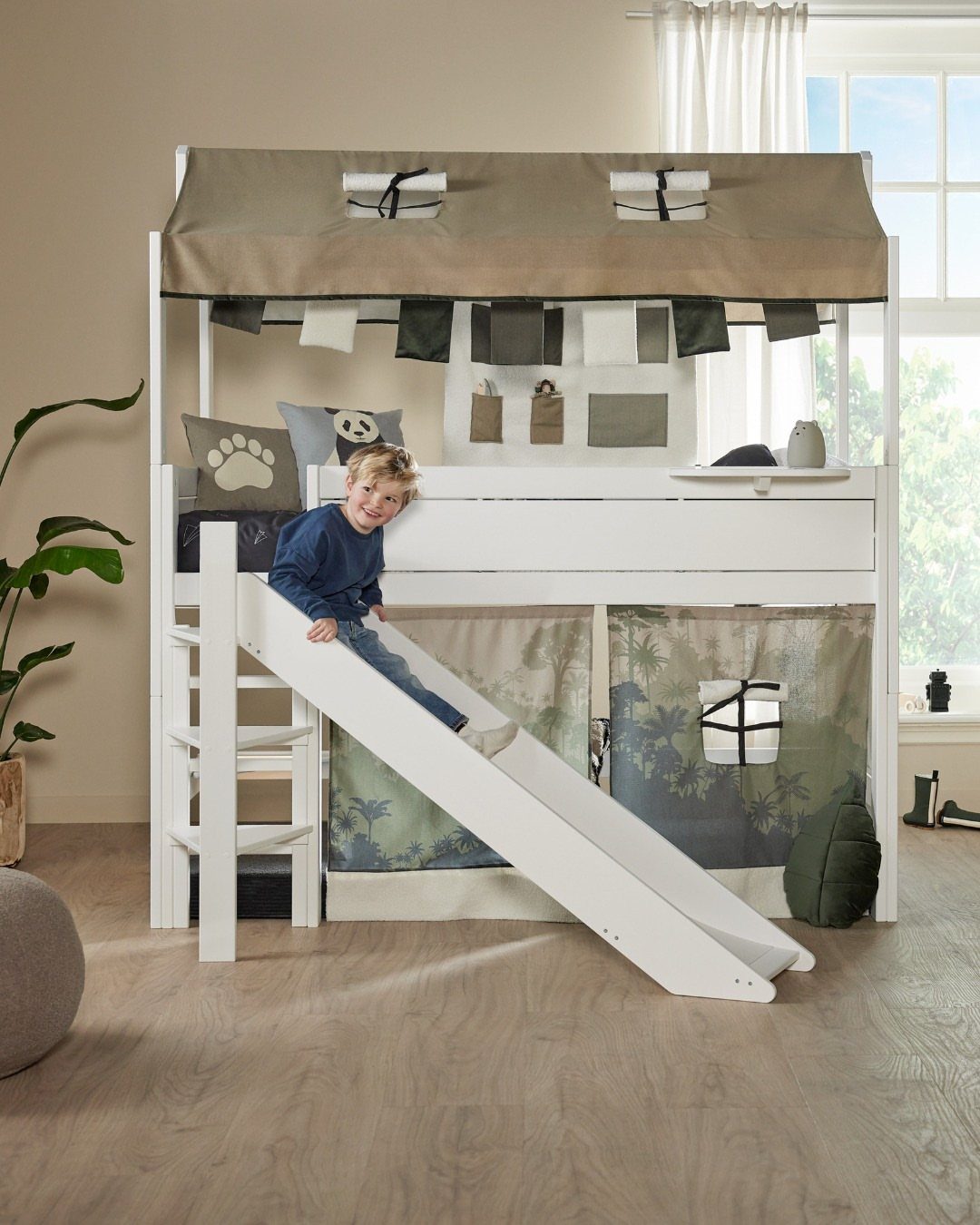 White wooden loft bed with a slide and a child sliding down.