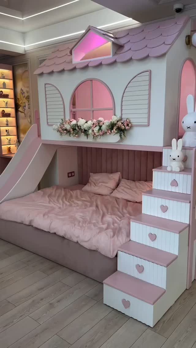 Pink and white house-shaped loft bed with a slide and heart-decorated stairs.