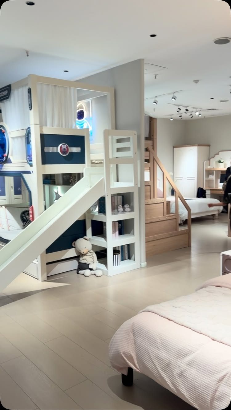 White and blue loft bed with a slide and shelving in a showroom.