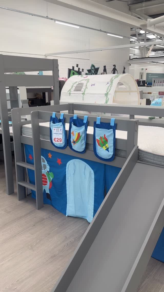 Grey low loft bed with a slide and blue space-themed under-bed curtain.
