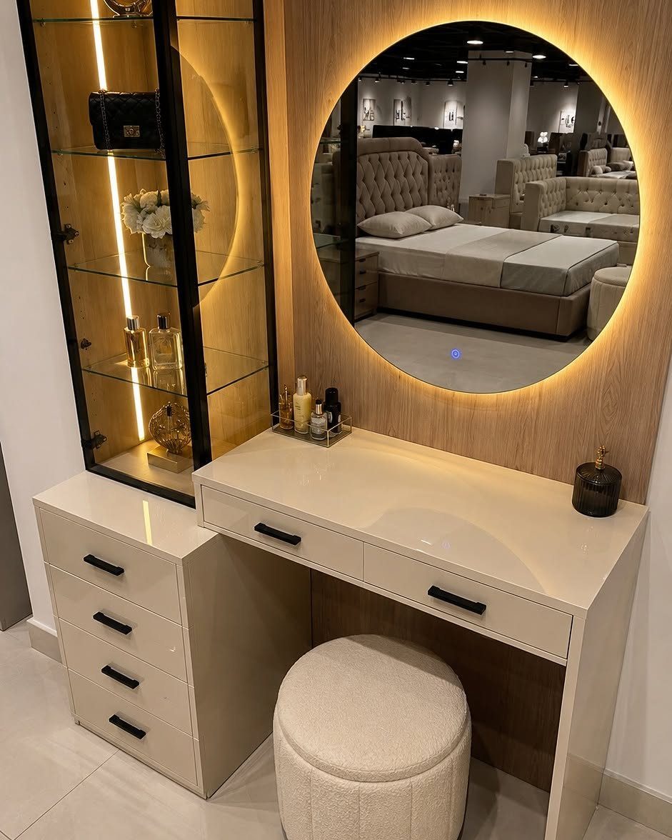 White dressing table with round backlit mirror and matching upholstered stool.