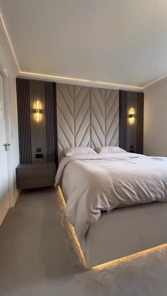 Beige upholstered headboard with chevron pattern in a modern bedroom with wood paneling.