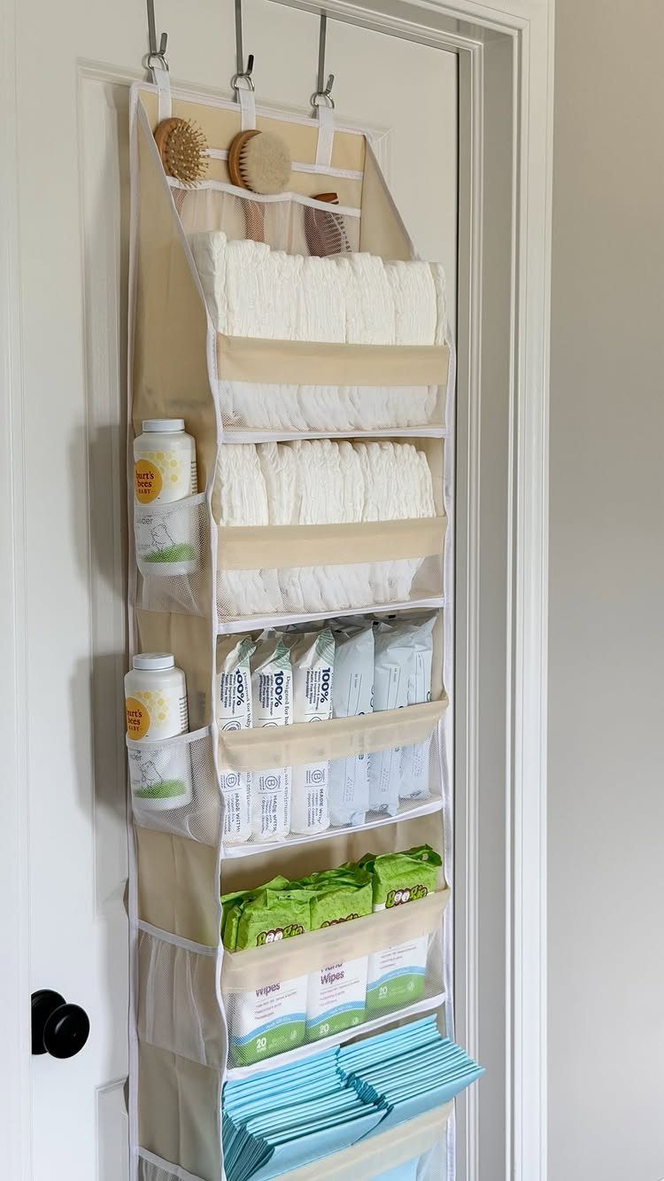 Beige hanging door organizer filled with diapers and baby supplies in a small space.