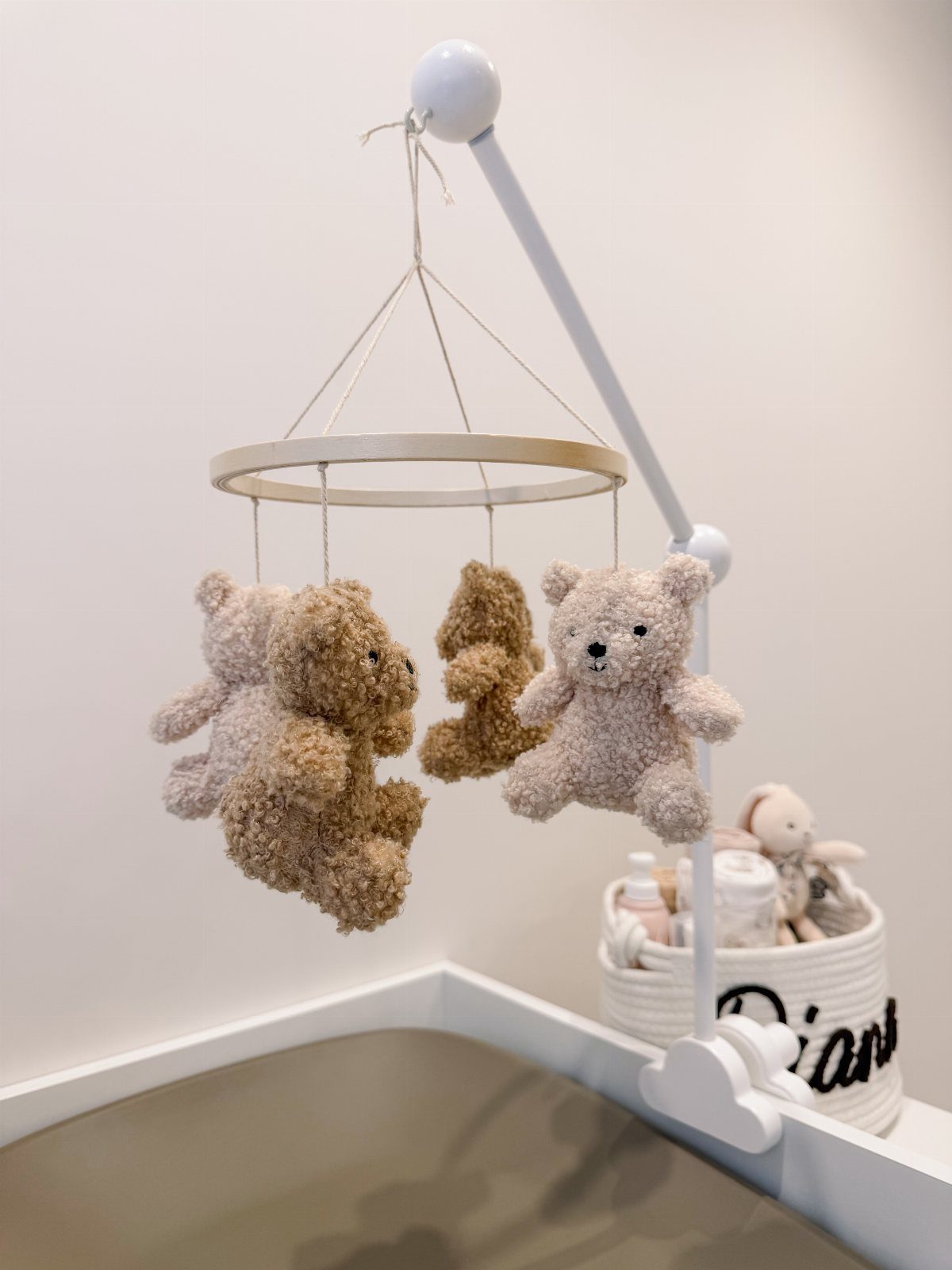 Teddy bear baby mobile hanging over a crib in a white nursery room