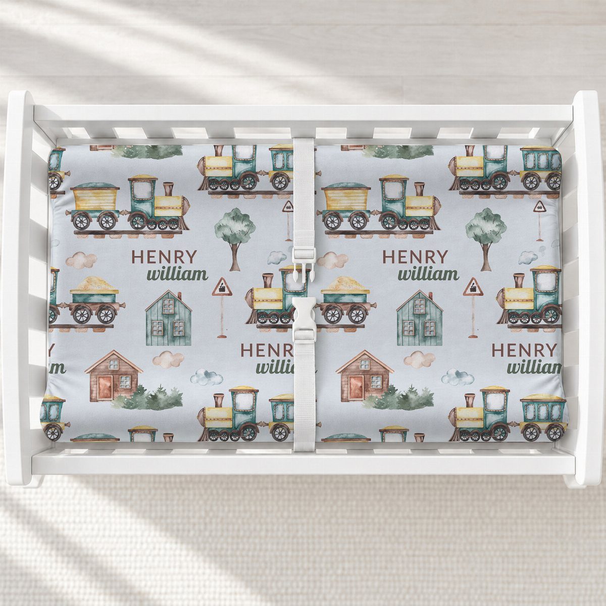 White changing table with a blue train patterned changing pad for a baby.