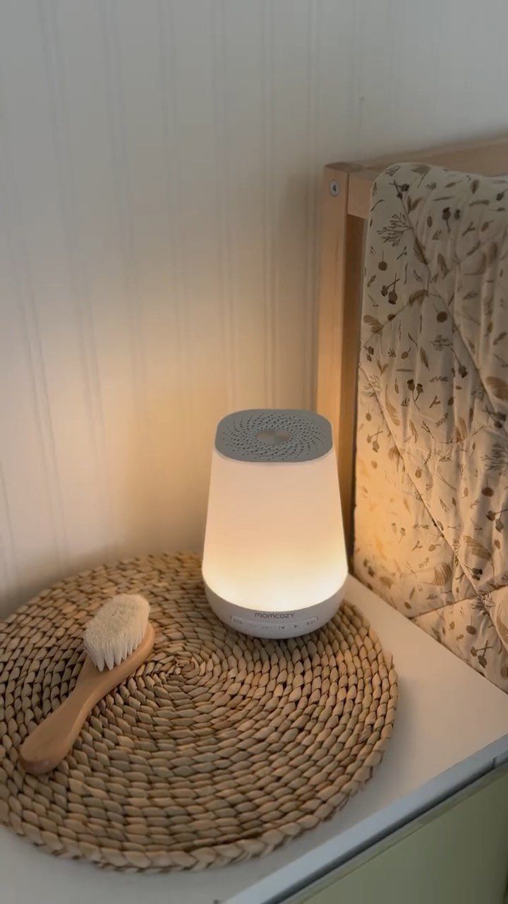 White glowing sound machine and baby brush on a woven mat by a crib
