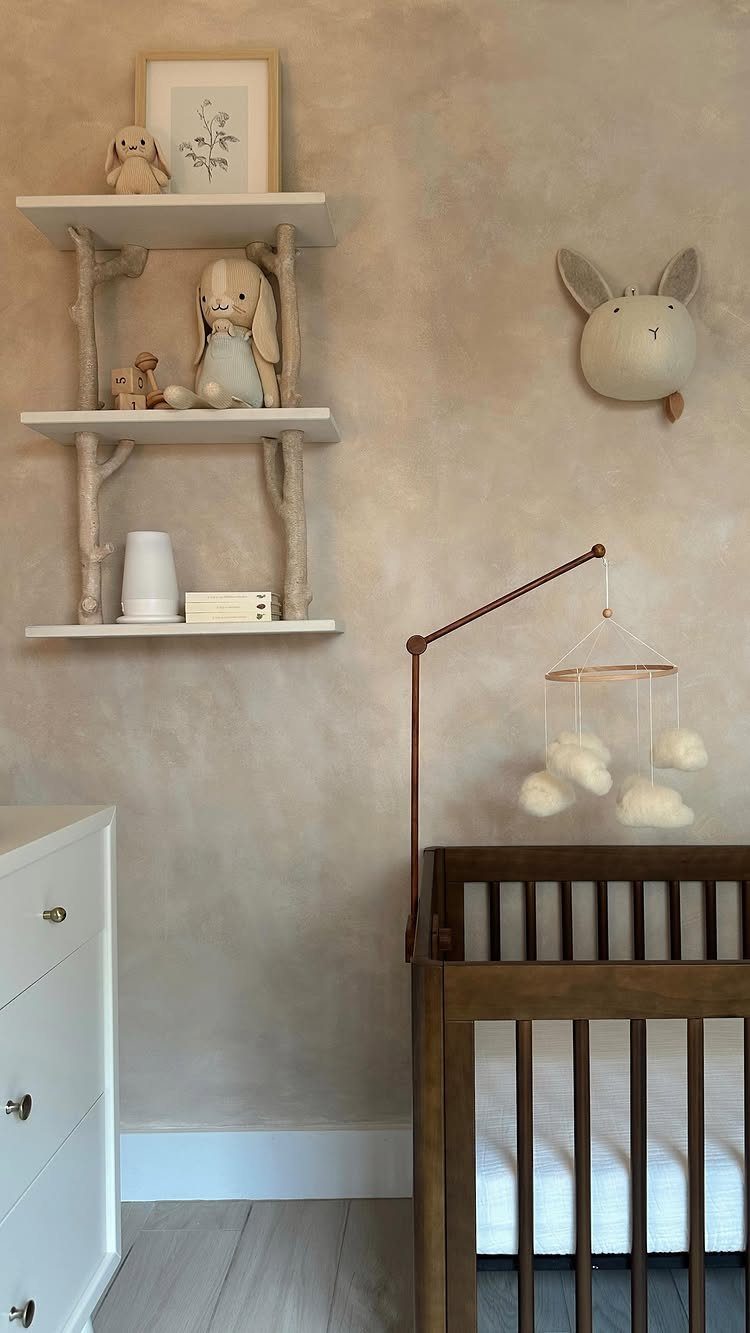 Dark wood crib and white floating shelves in a neutral toned nursery room.
