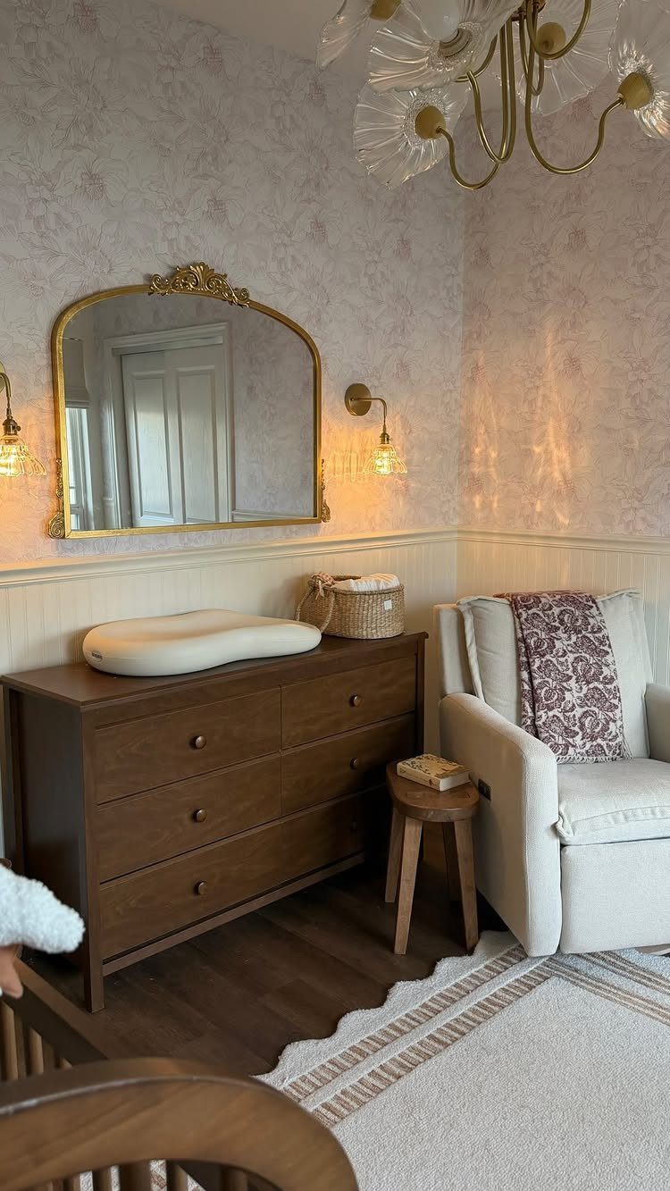 Nursery interior with a gold chandelier, wall sconces, and dark wood furniture.