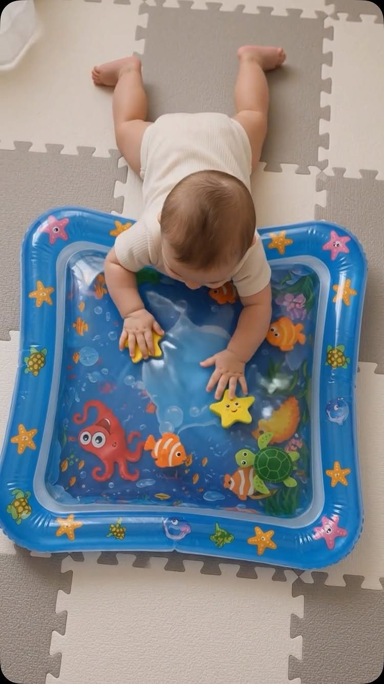 Baby playing with a blue inflatable water mat filled with colorful sea creature toys.