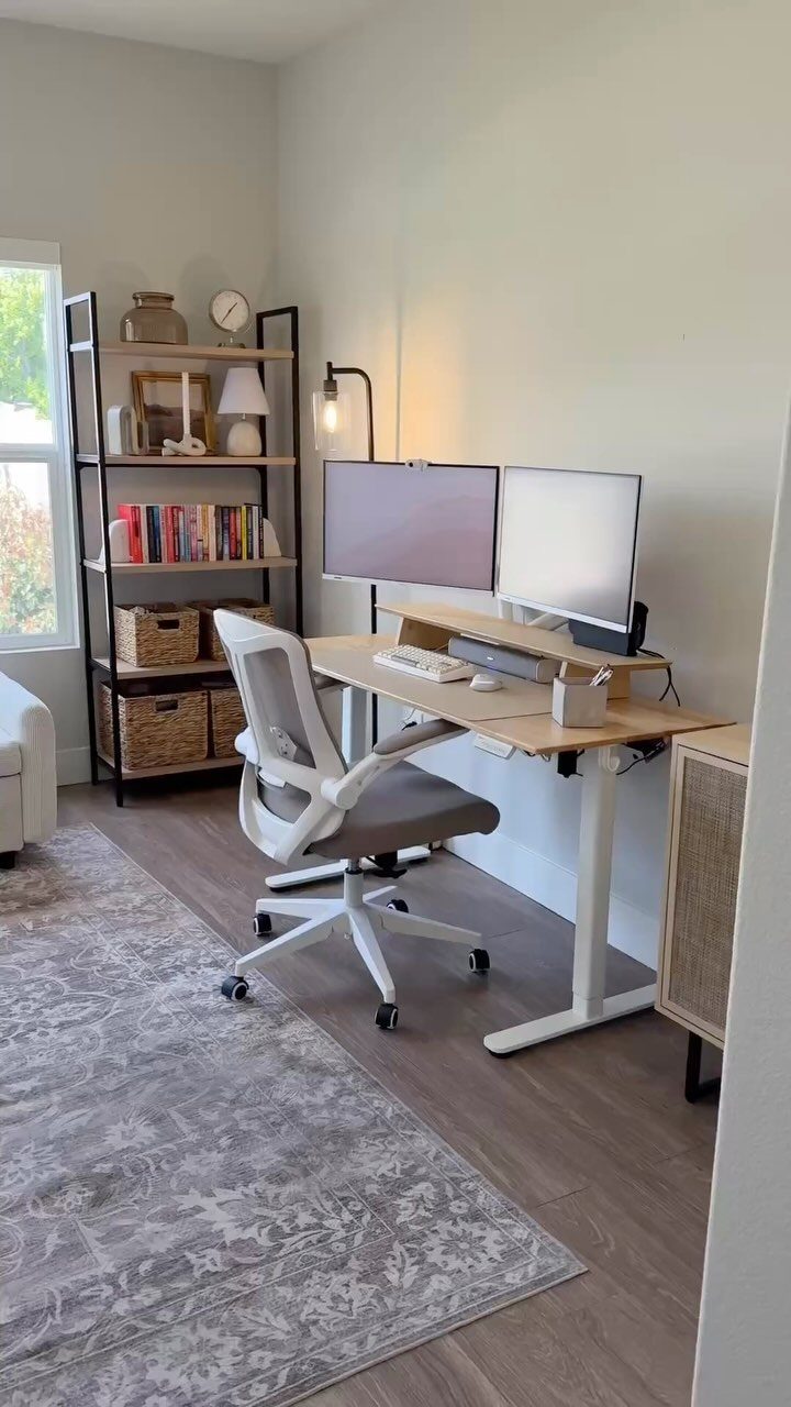 Adjustable standing desk with dual monitors and ergonomic chair in a bright room.