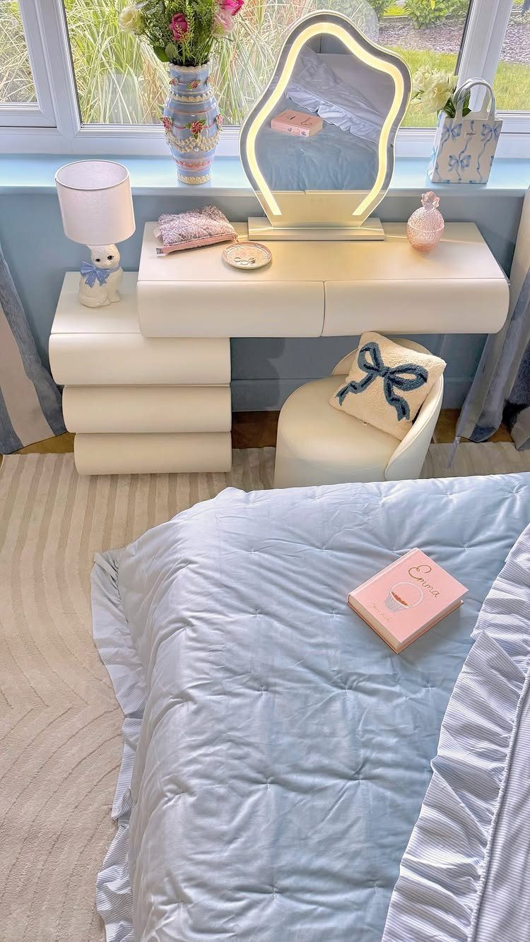White vanity desk with light-up mirror and light blue quilted bedding in bedroom