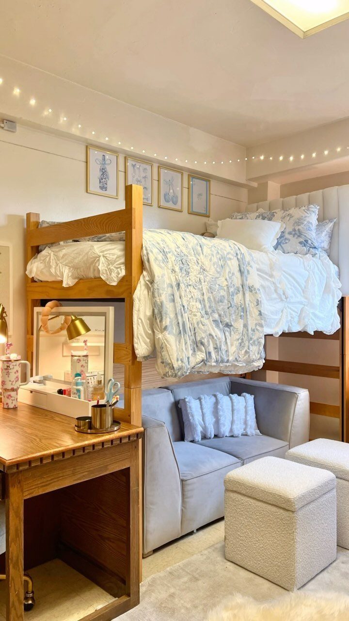 Loft bed with blue floral bedding over a light blue sofa in a dorm.