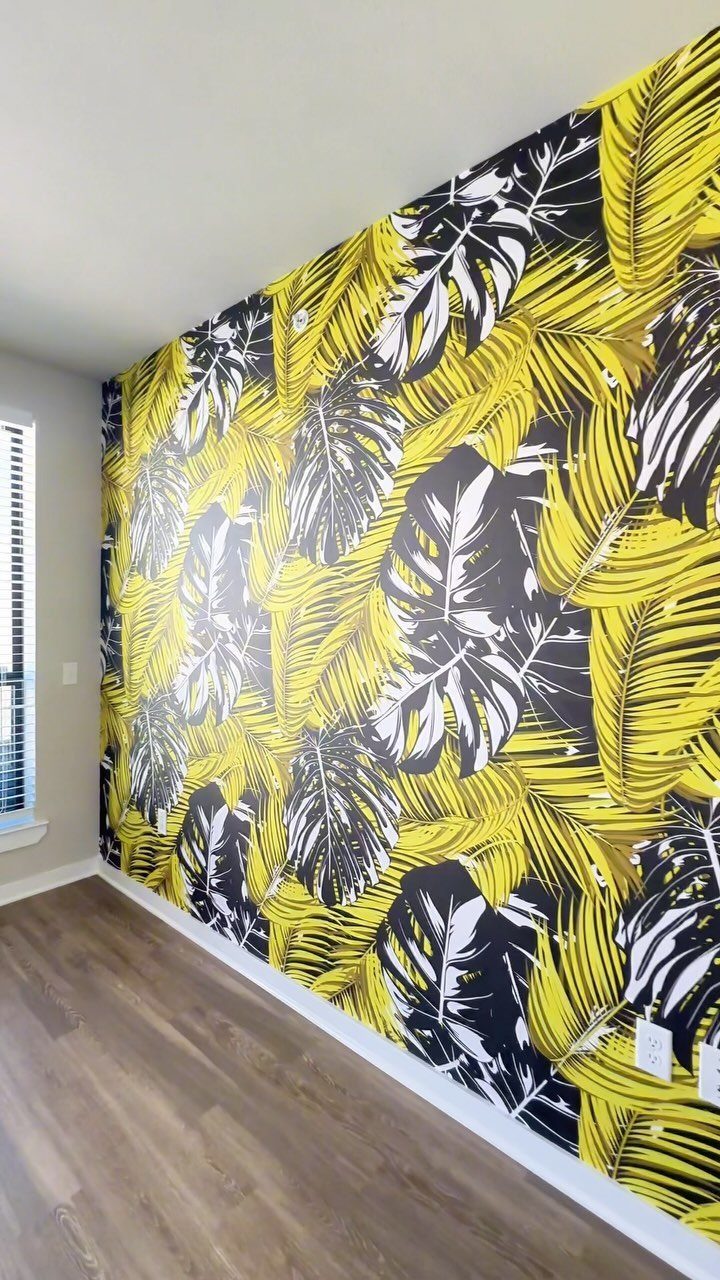 Tropical leaf wallpaper in yellow, white, and black covering a room wall.