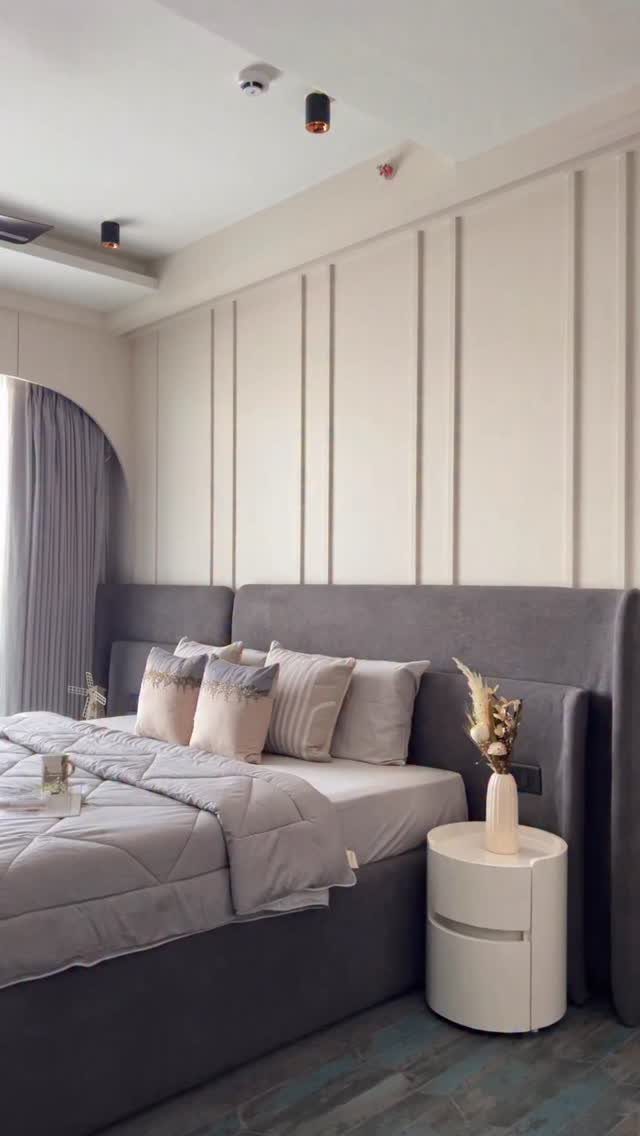 Modern bedroom with a grey upholstered bed and cream vertical wall paneling.
