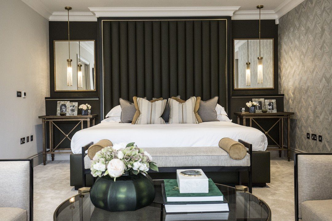 Luxury bedroom with matching nightstands, gold pendant lamps, and a dark fluted headboard.