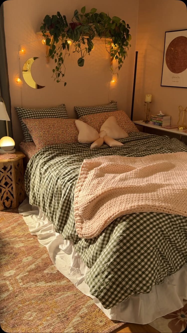 Bedroom with green gingham bedding, pink pillows, and hanging plants with fairy lights.