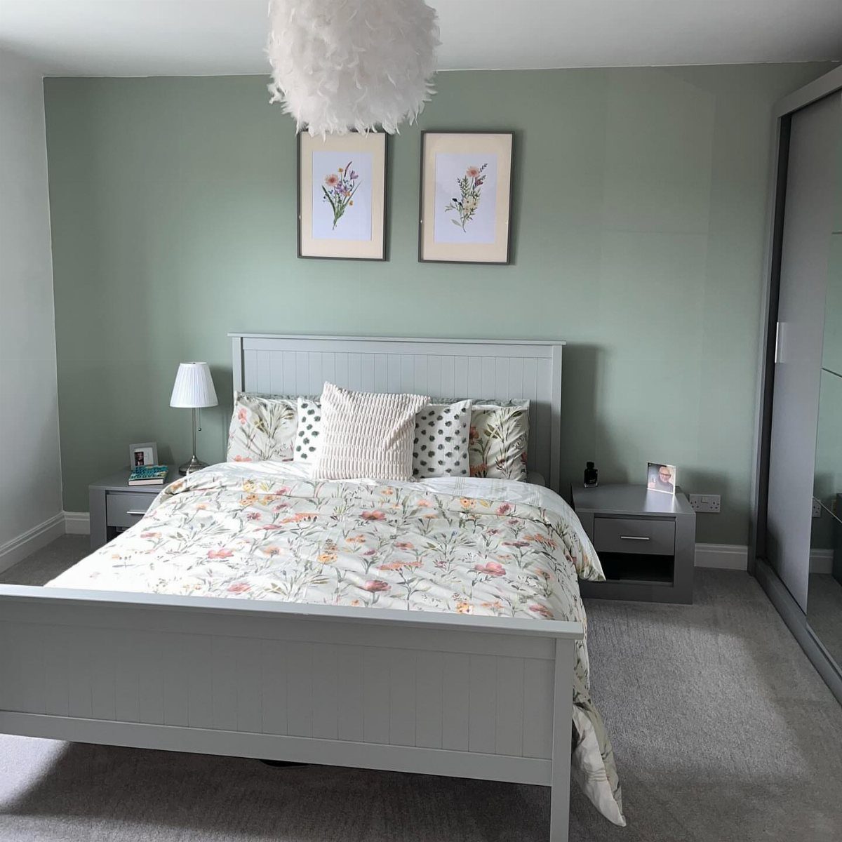Sage green bedroom with grey bed, floral bedding, and matching botanical wall art.