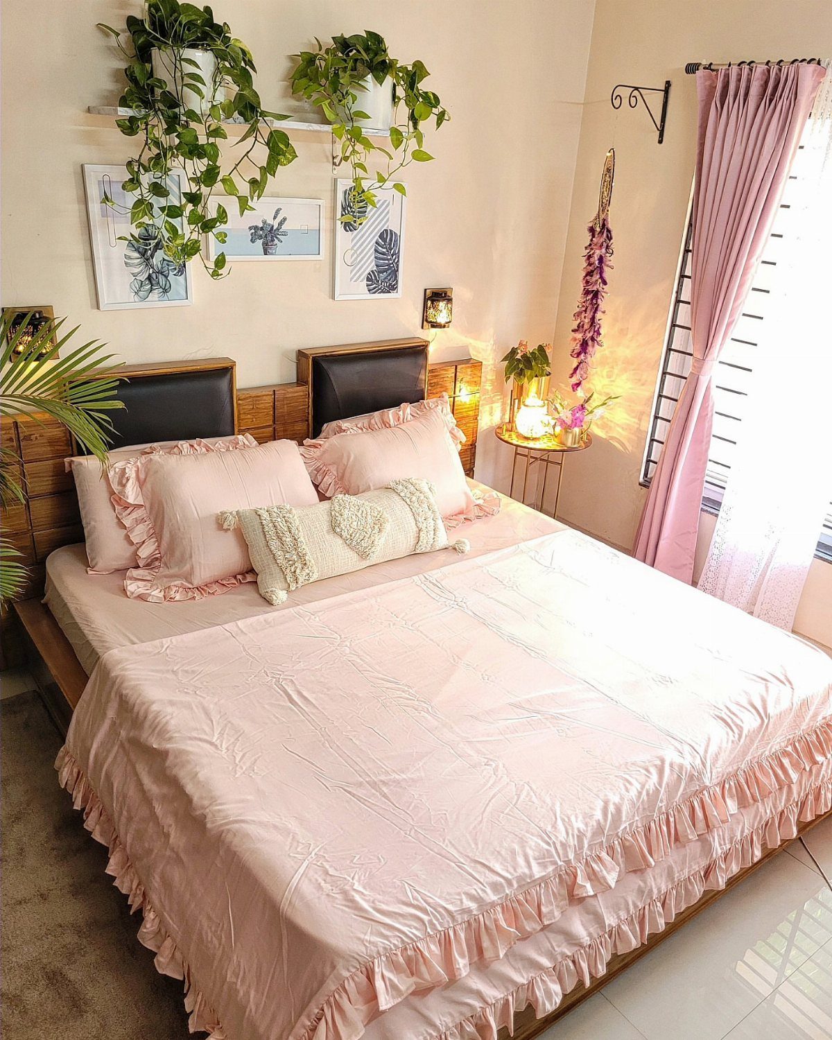 Bed with pink ruffled bedding and hanging green plants on a wall shelf.