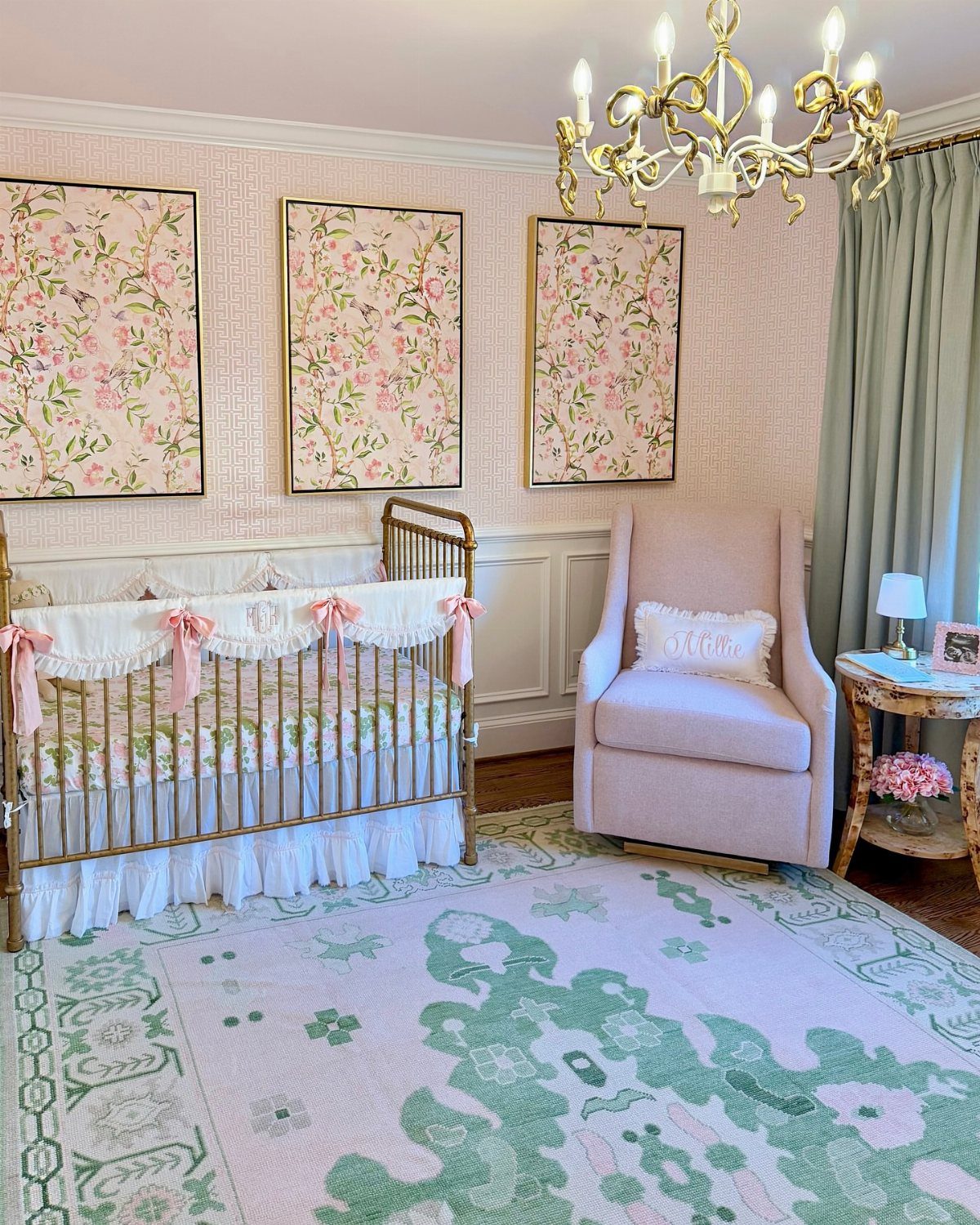 Nursery room with pink and green color palette, gold crib, and floral art.
