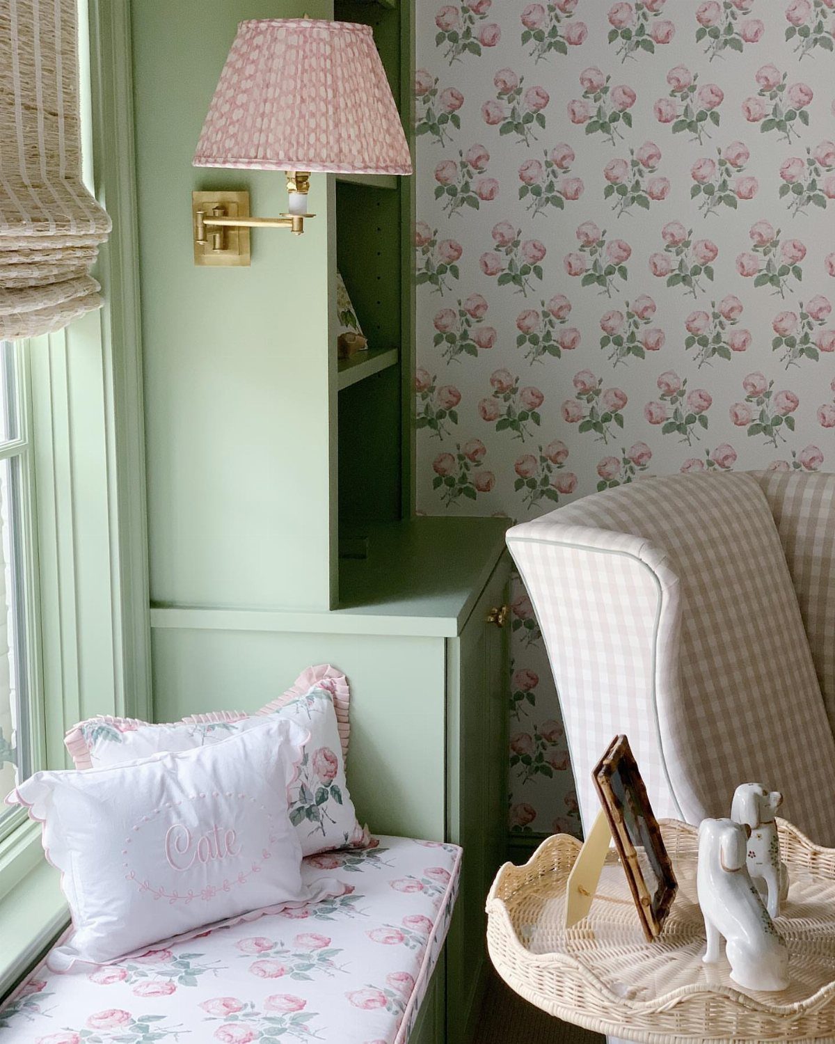 Sage green wooden cabinetry and floral pink fabric cushions in a nursery setting