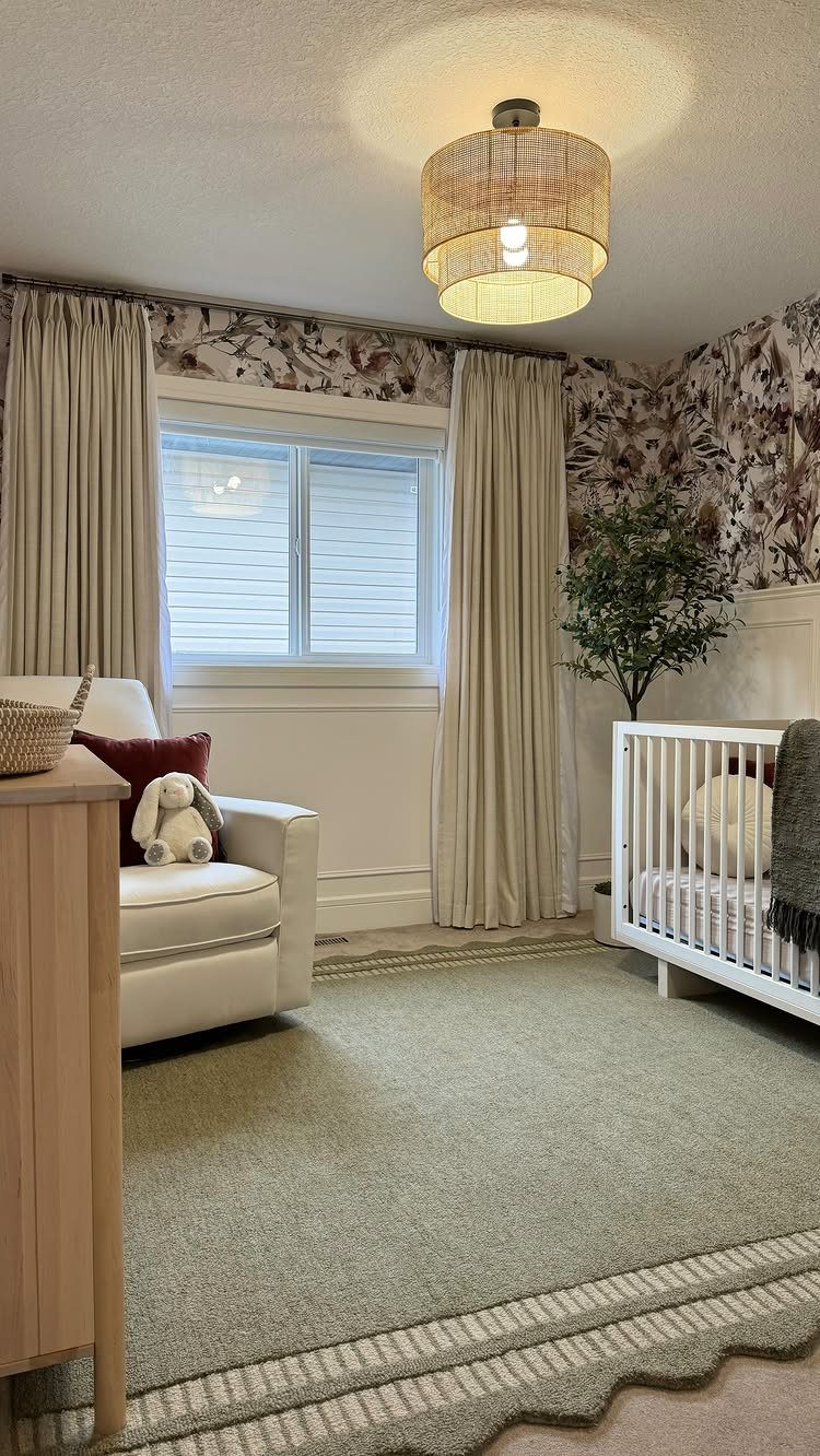 Light green scalloped rug in a nursery with white furniture and floral wallpaper.