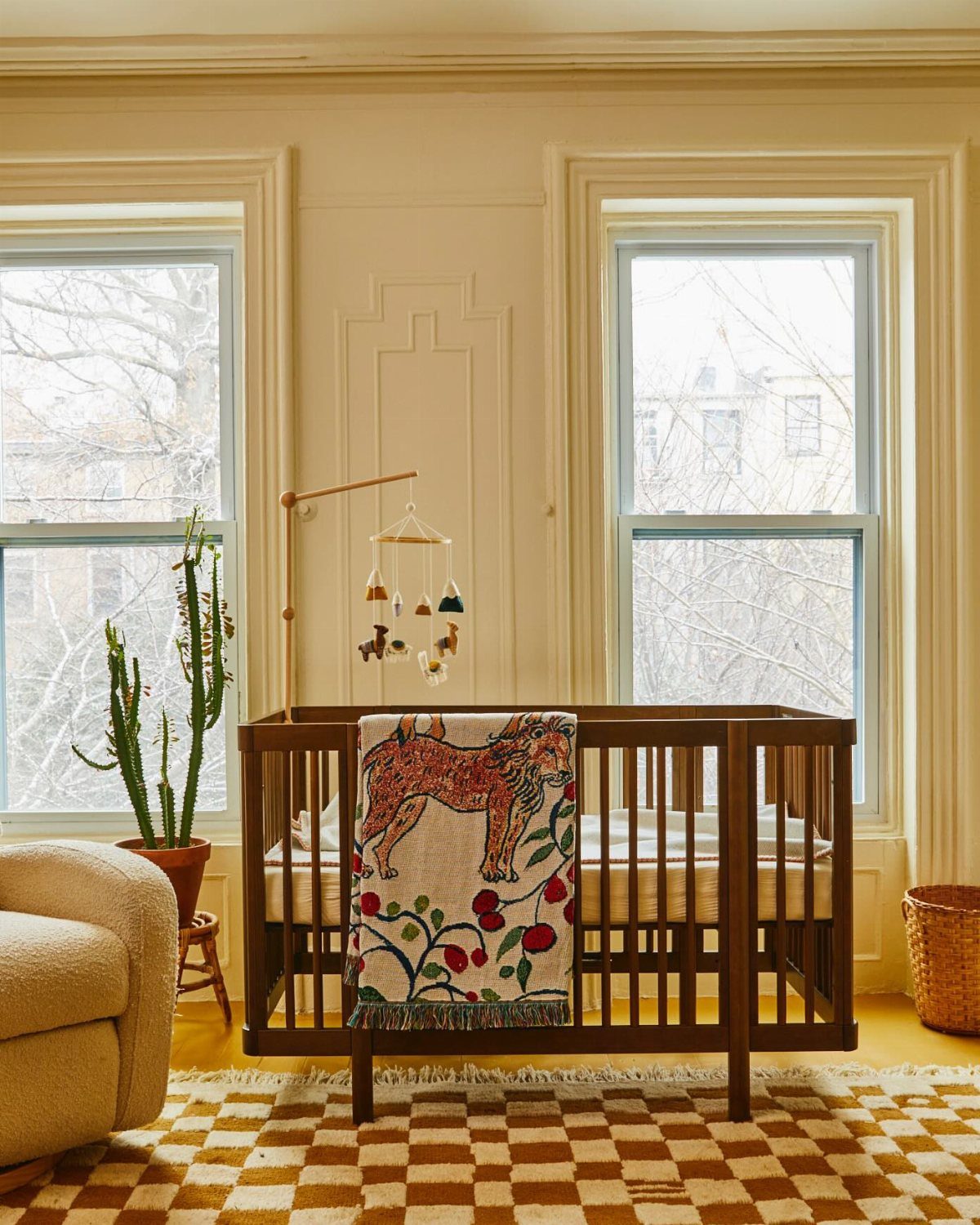 Checkered brown and cream rug placed under a dark wood baby crib in nursery