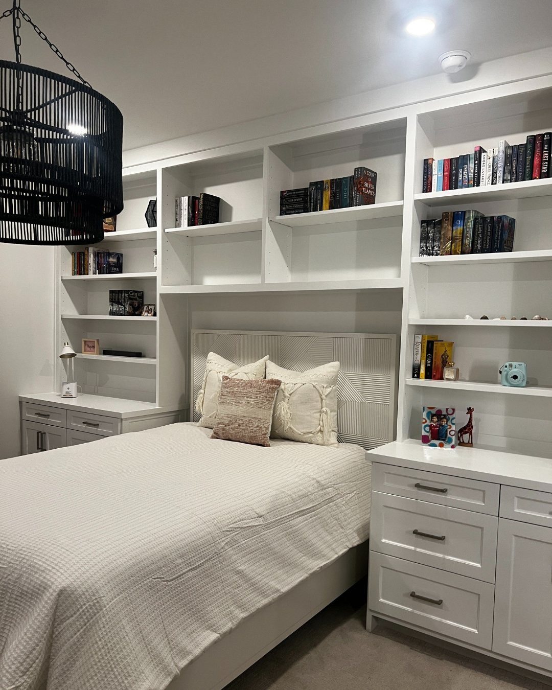 White built-in shelving surrounding a bed with a white textured bedspread and pillows.