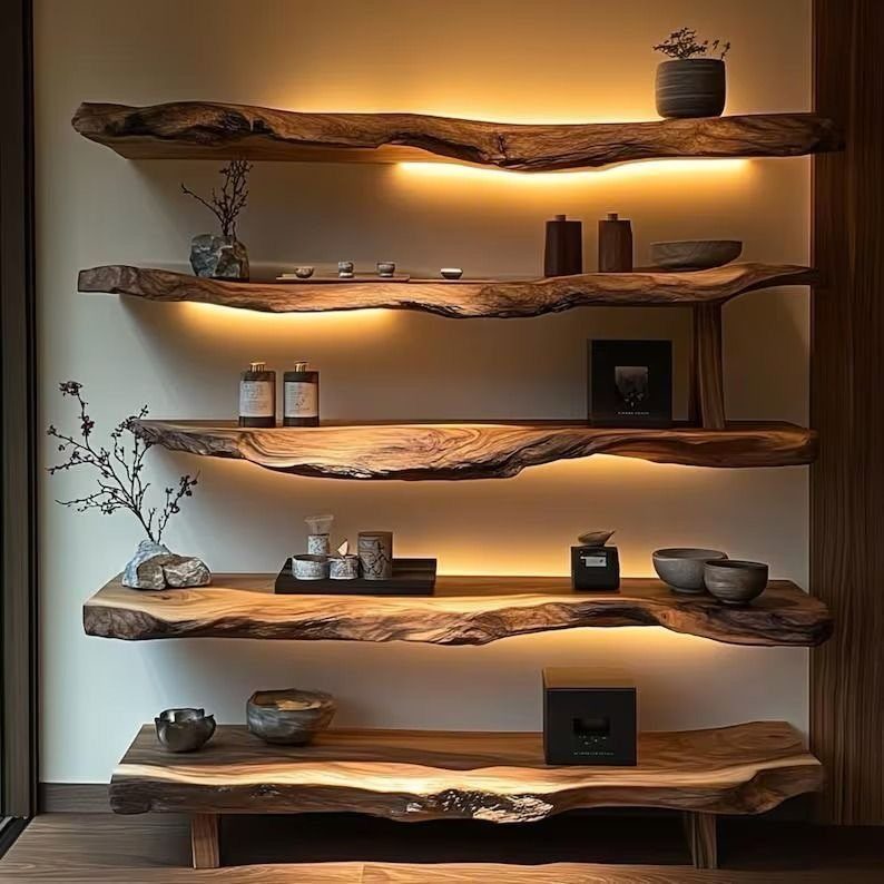 Live-edge wooden shelves with warm under-lighting holding decorative bowls and vases on a wall.