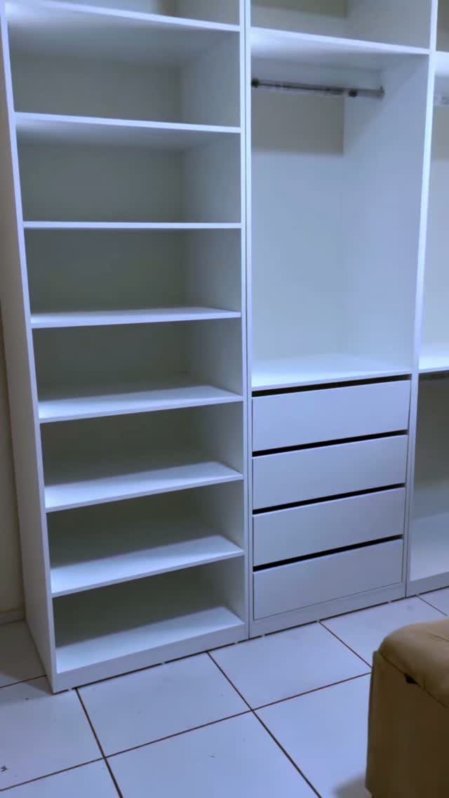 White modular closet system with open shelving and drawers on a tiled floor.