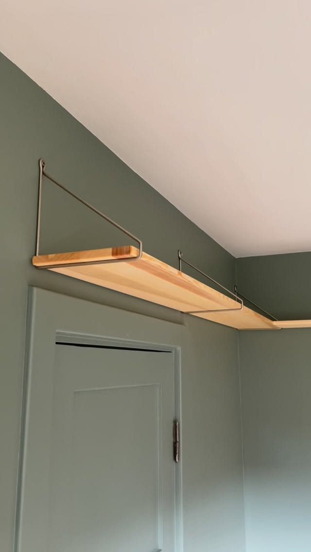 Wooden wall shelf with metal brackets mounted above a white interior door.