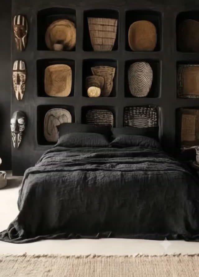 Recessed wall niches containing woven baskets and wooden bowls above a dark bed.