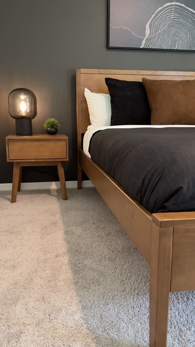Dark grey accent wall in a bedroom with wooden furniture and neutral carpet.