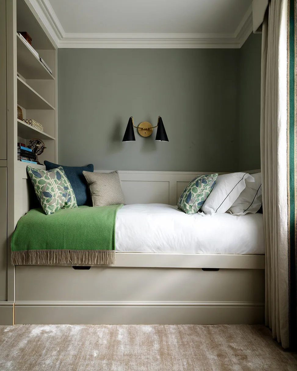 Cozy small guest bedroom nook with a daybed, green throw, and built-in shelving.